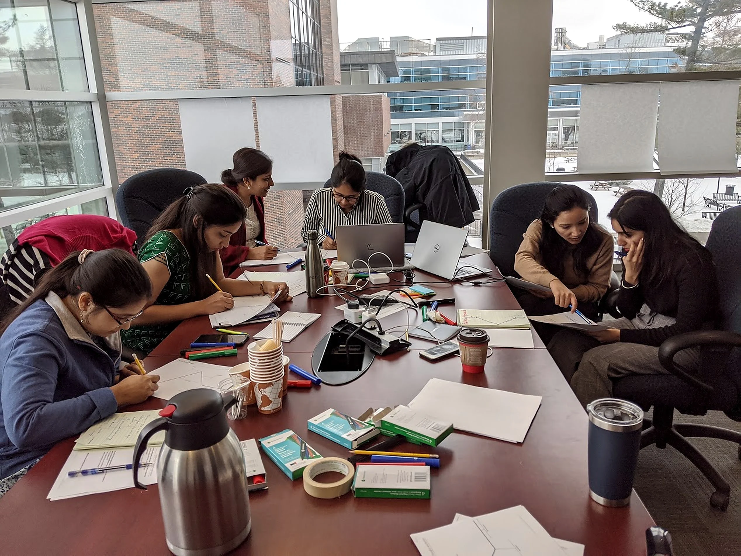 Participants working around a table with charts, papers and laptops