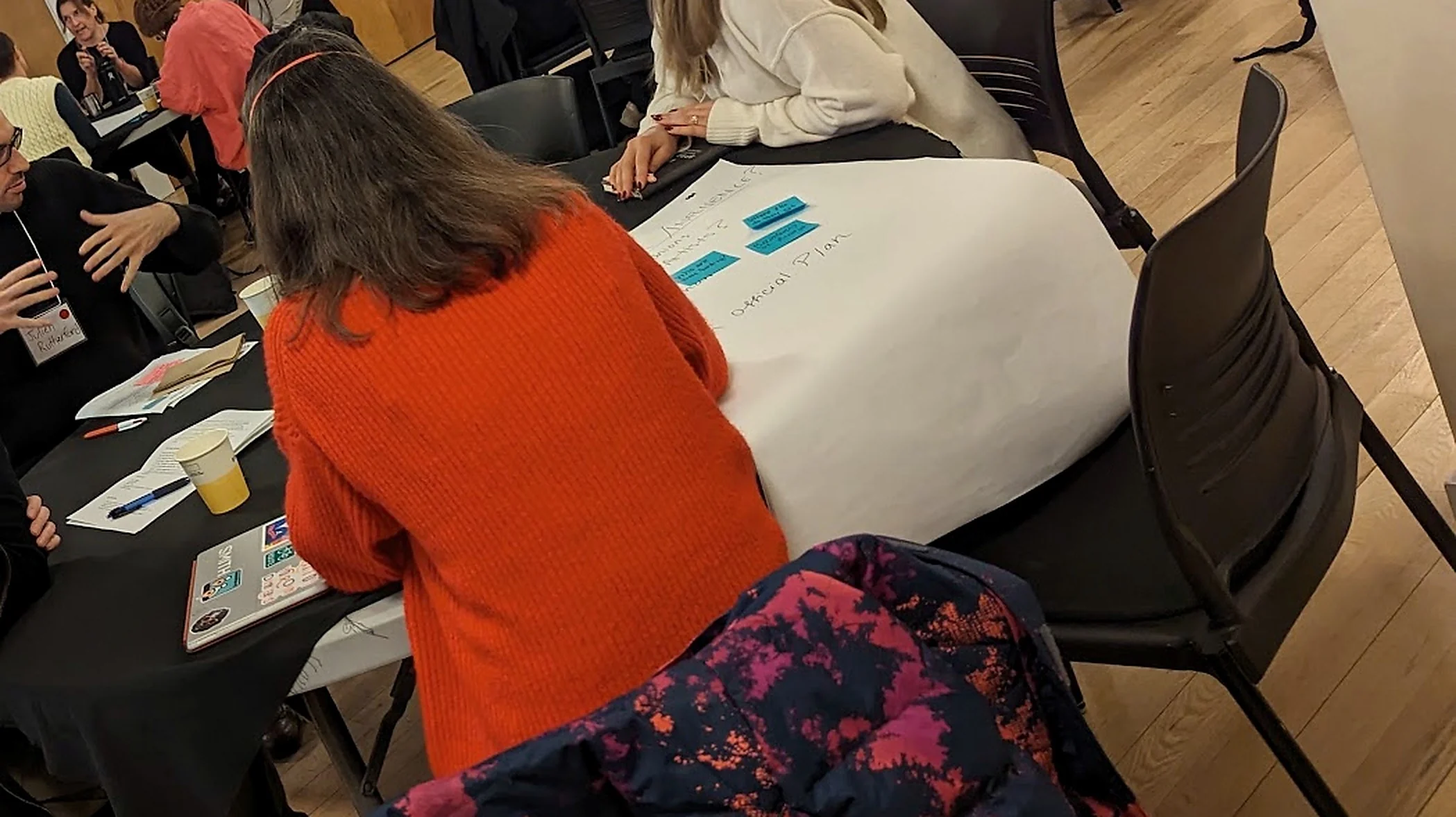 Round tables in a community hall, participants in discussion over a planning chart