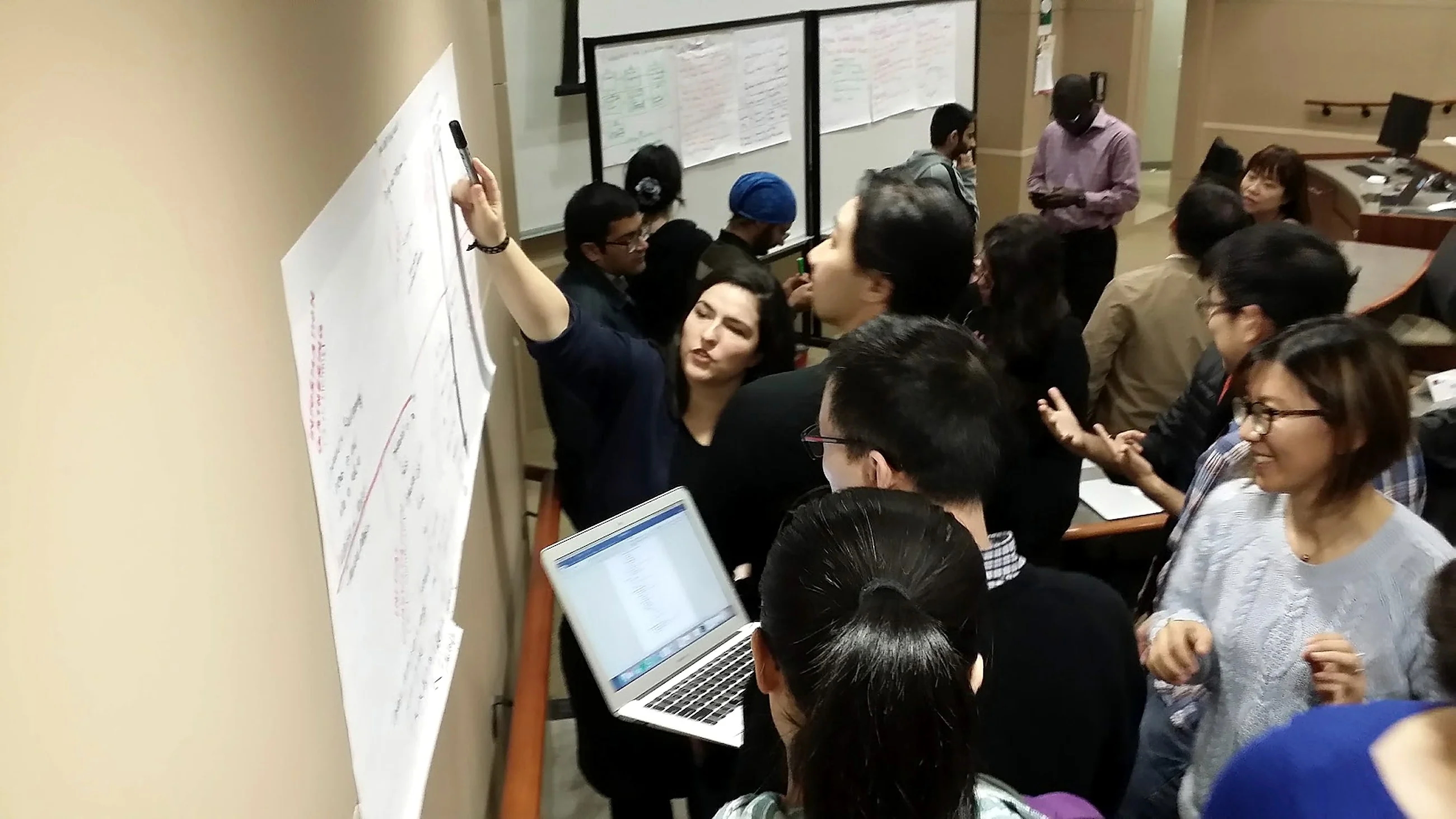 A group standing at a wall of written notes during a working session